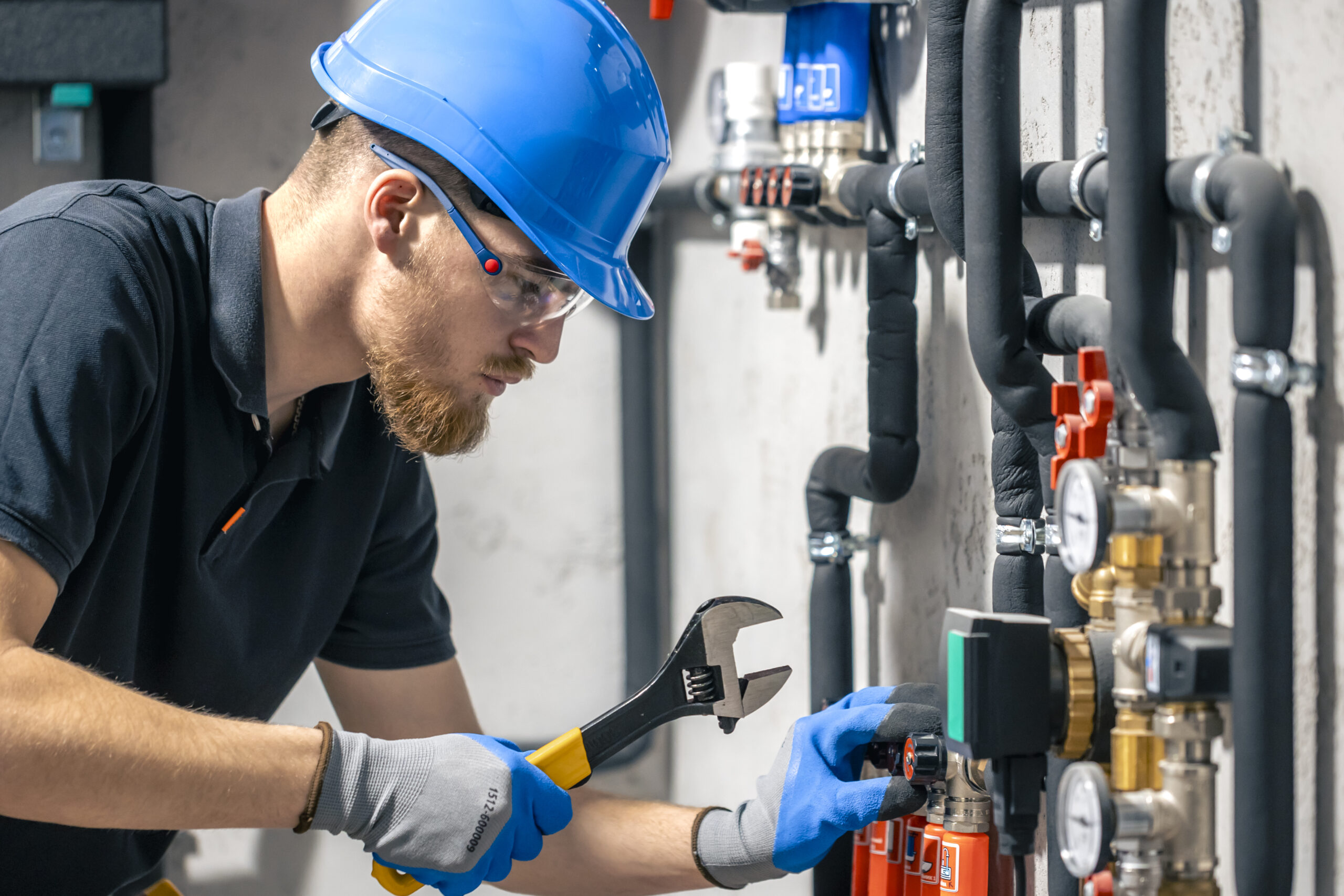 man installs heating system house checks pipes with wrench scaled